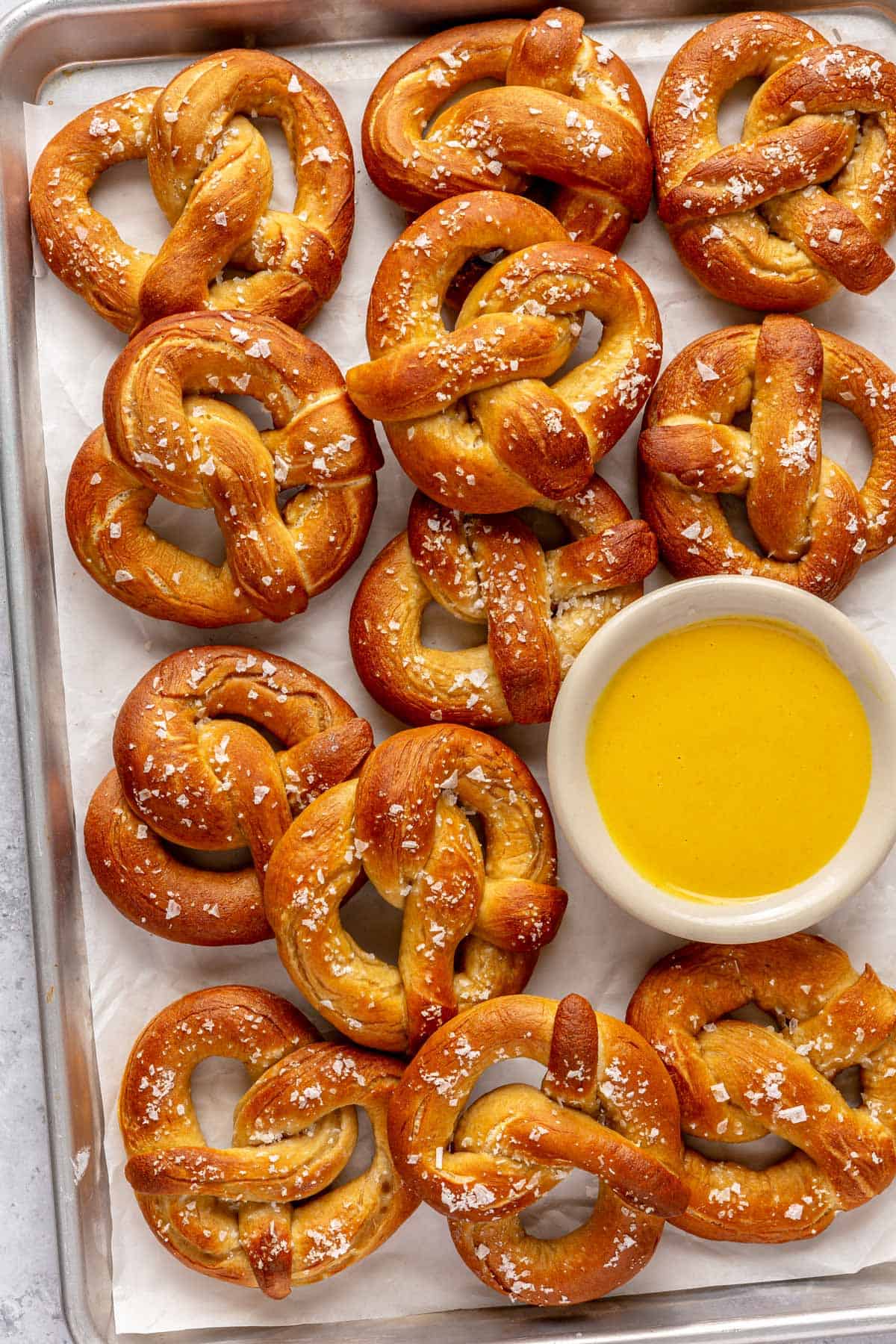 Easy soft pretzels on a sheet pan with a mustard dipping sauce.