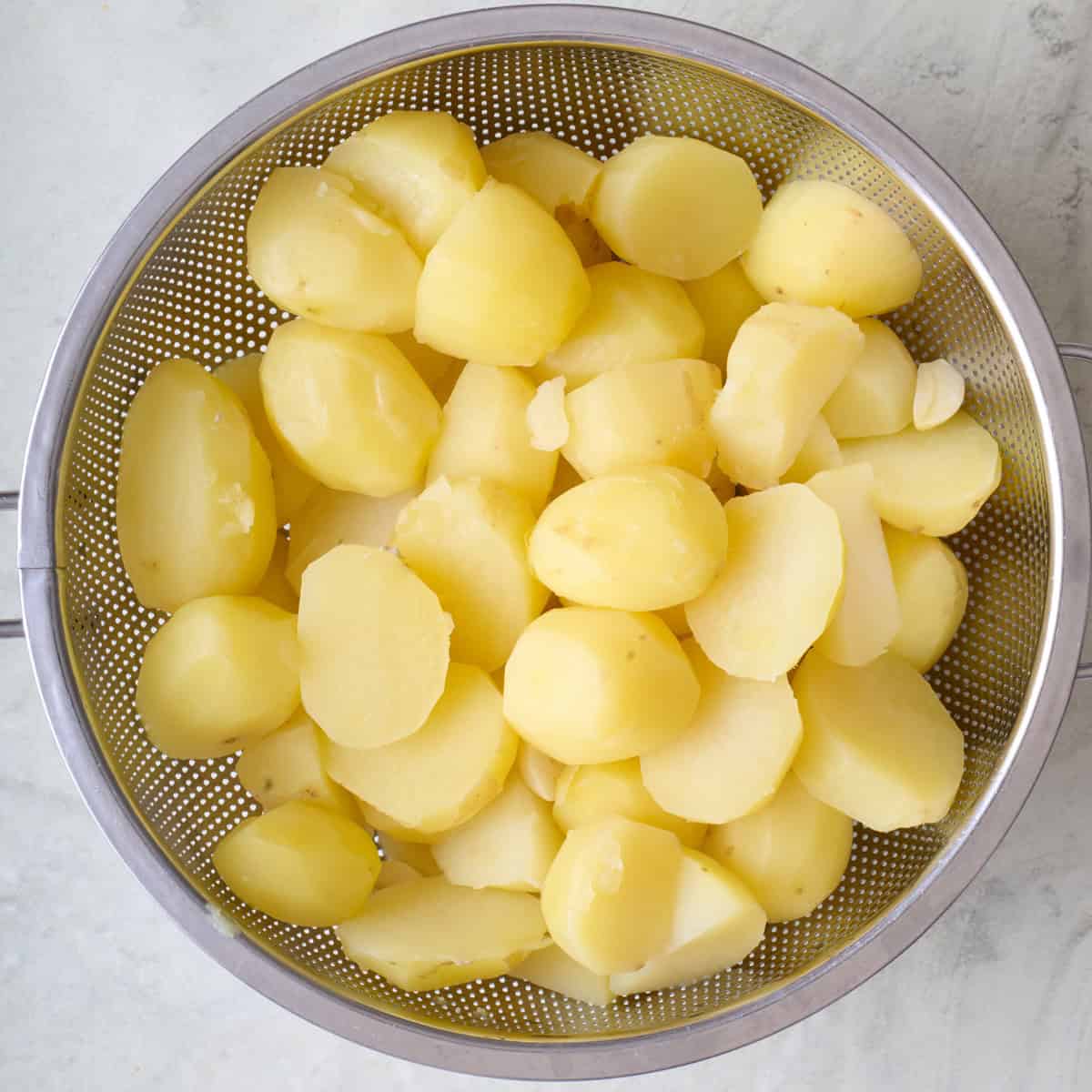 Cooked potatoes in colander.