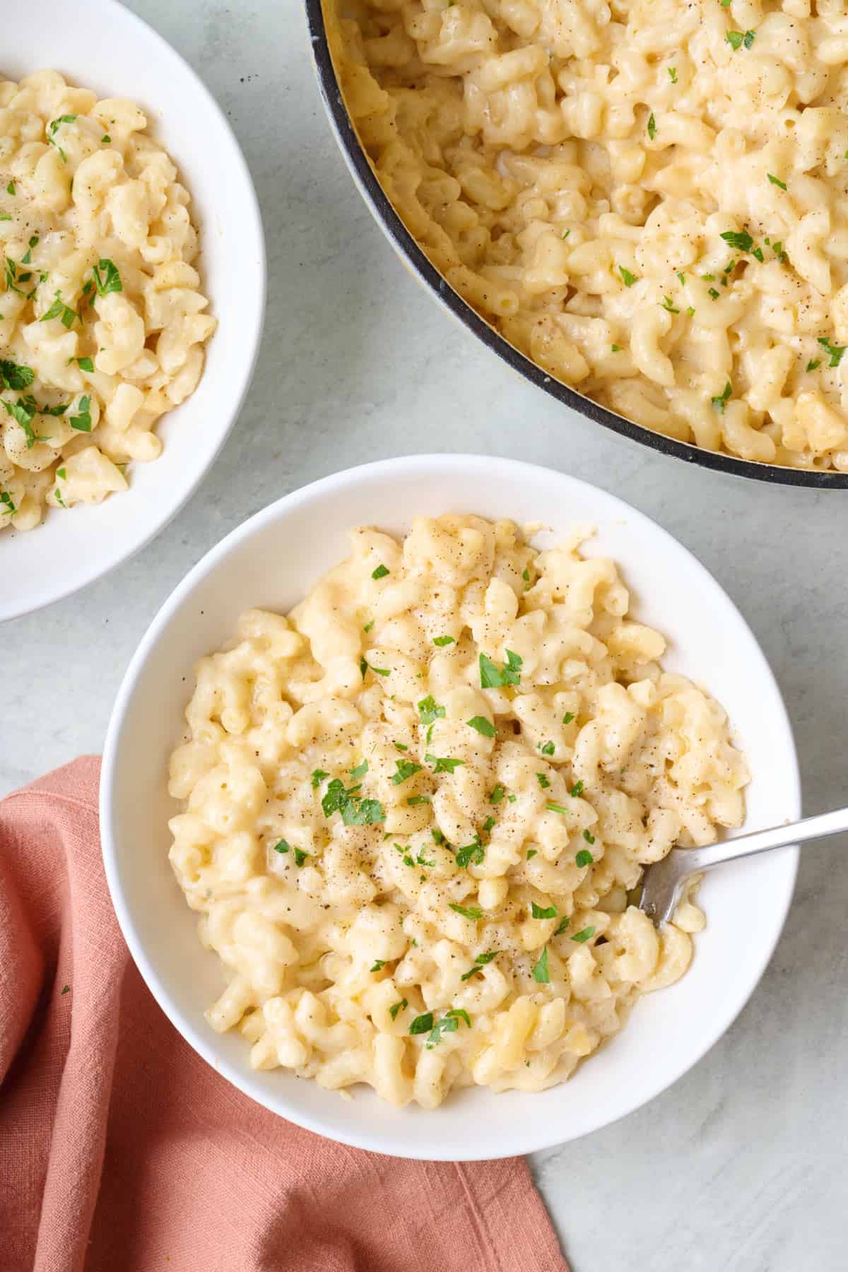 Two bowls of mac and cheese with a fork dipped inside dish.