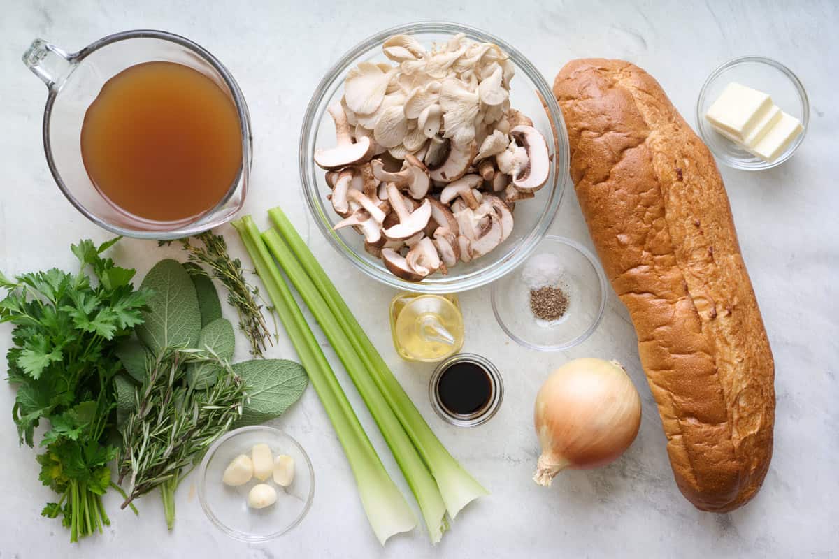 Ingredients for recipe: loaf French bread, butter, salt and pepper, onion, soy sauce, oil, sliced mushrooms, celery, fresh sage, thyme, and rosemary, garlic cloves, and broth.