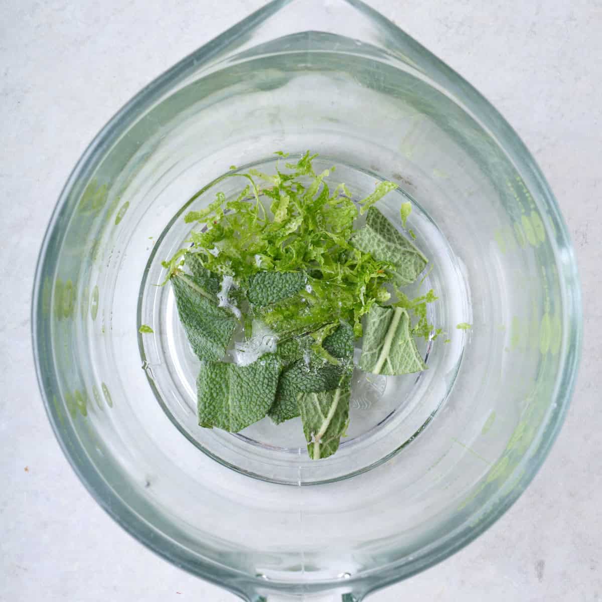 Fresh sage, lime zest and simple syrup in a glass.