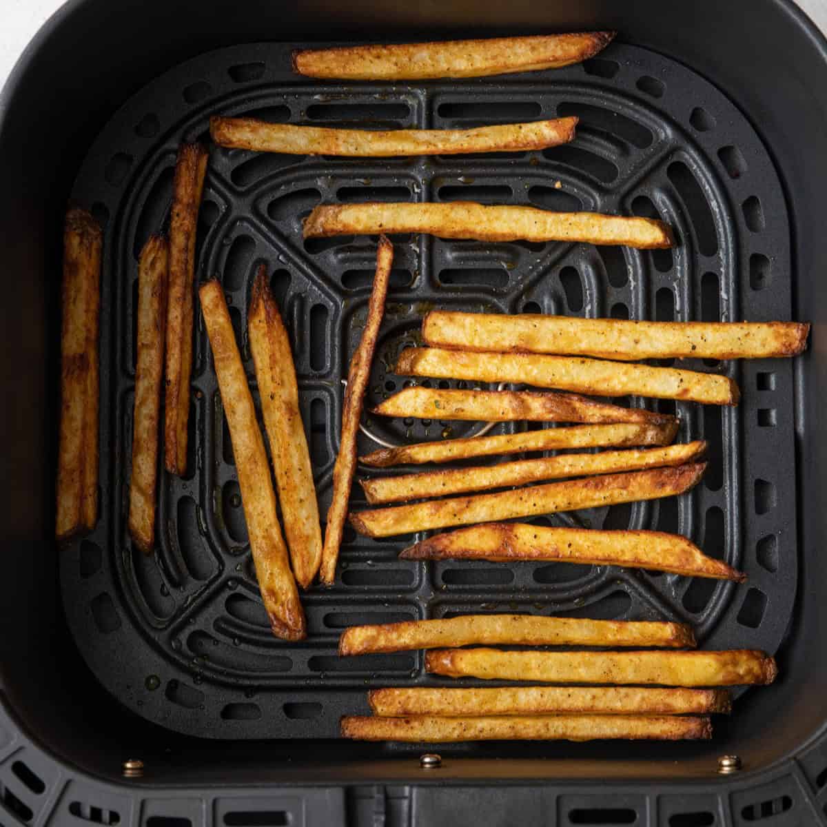 Seasoned fries in air fryer basket after cooking.