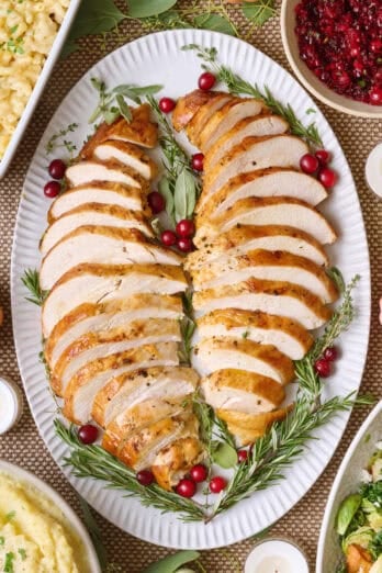 Air fryer turkey breasts sliced on a large holiday platter with fresh herbs.