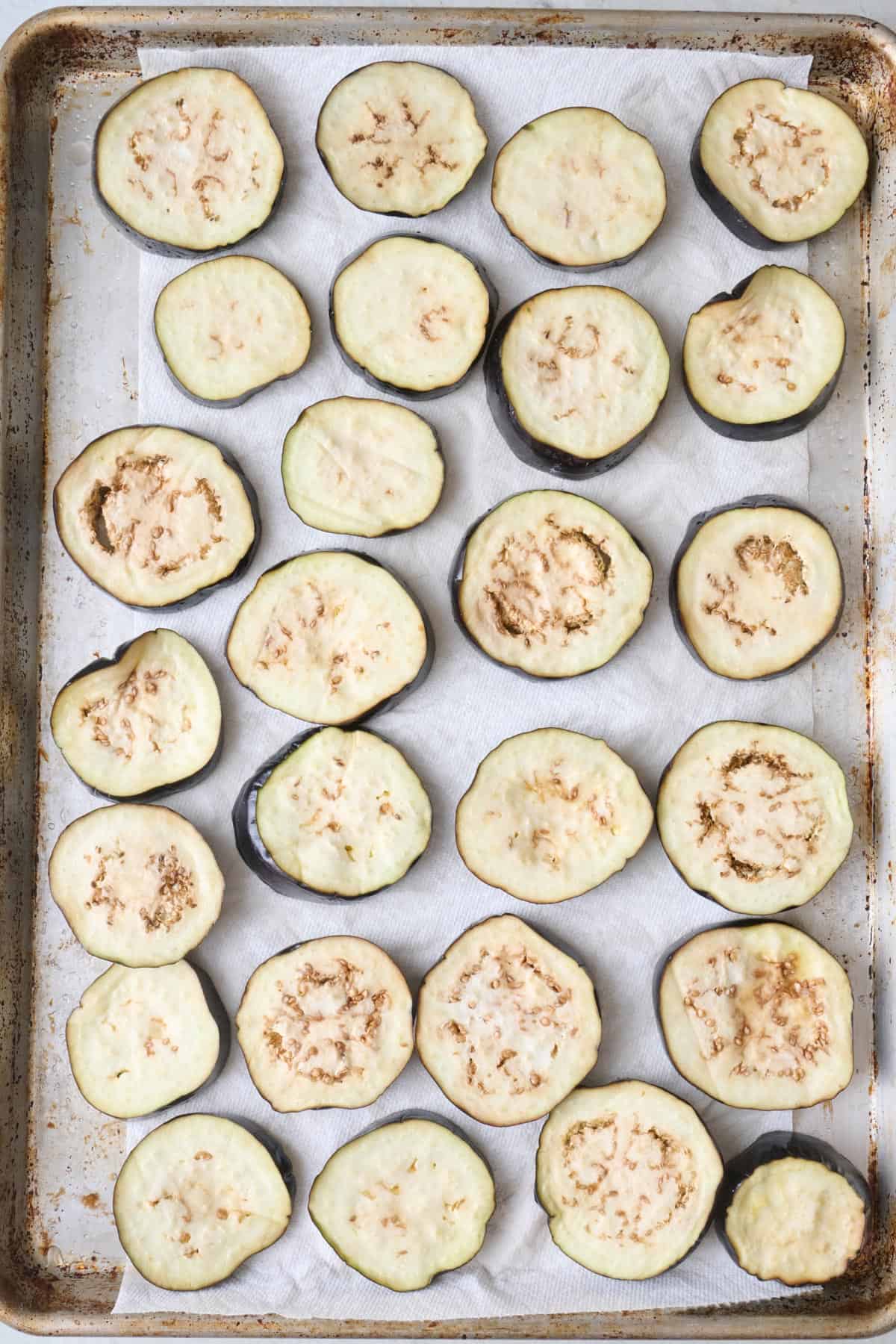 Sliced eggplant on a baking sheet with salt.