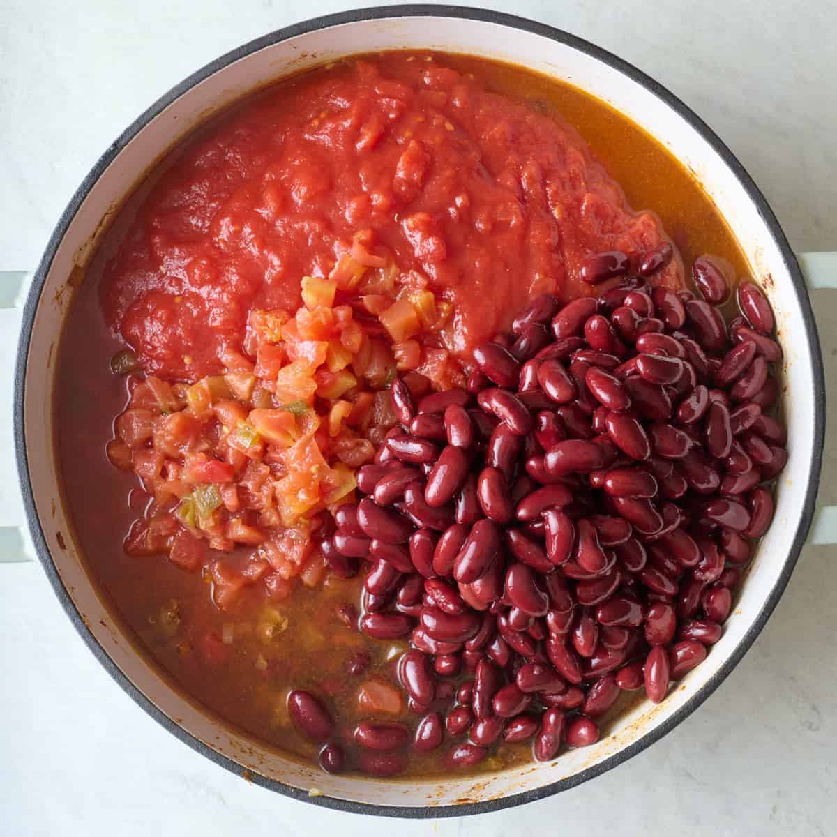 Beans, tomatoes, and water added to cooked beef and veggies.