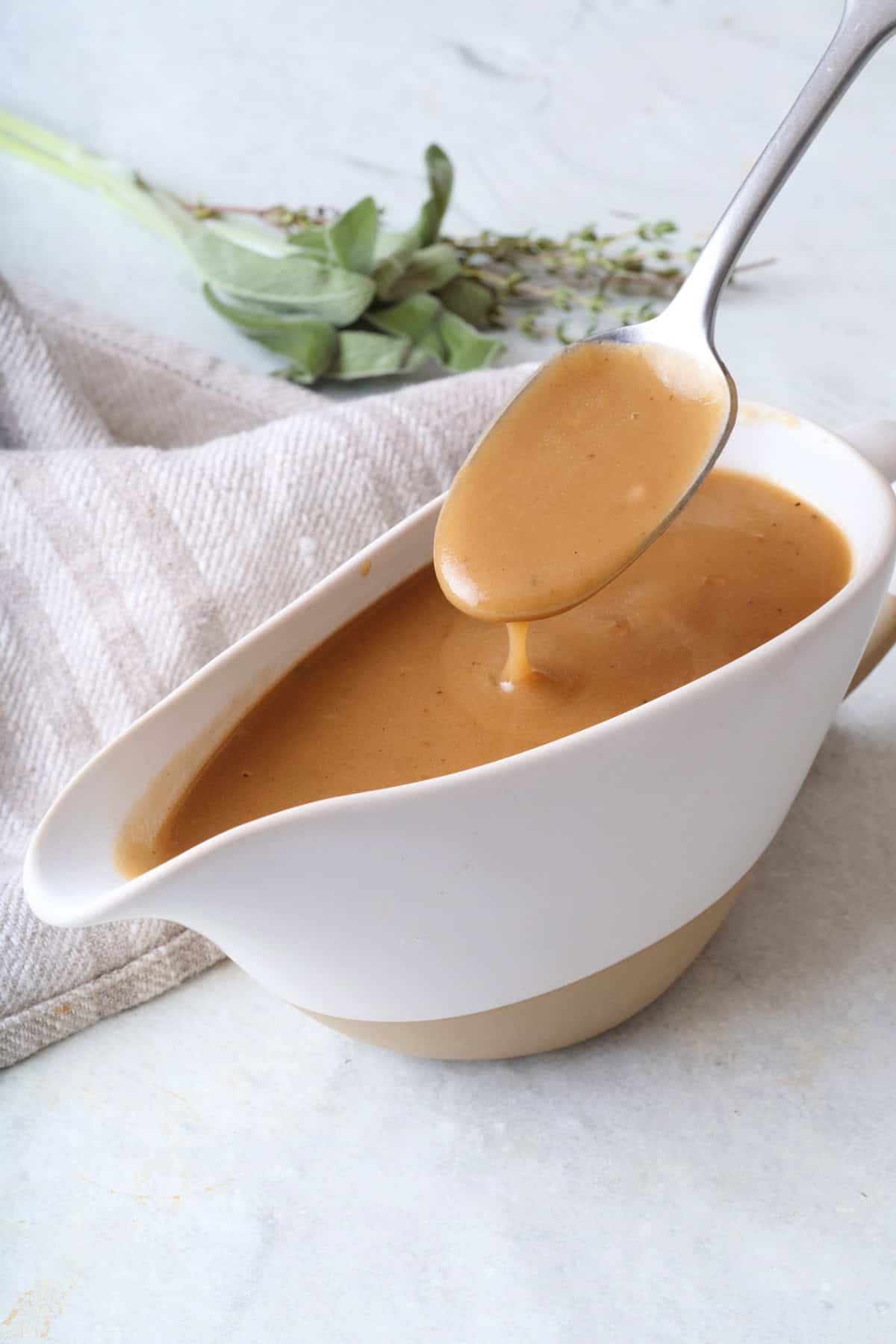 Lifting beef gravy with a spoon from gravy boat.