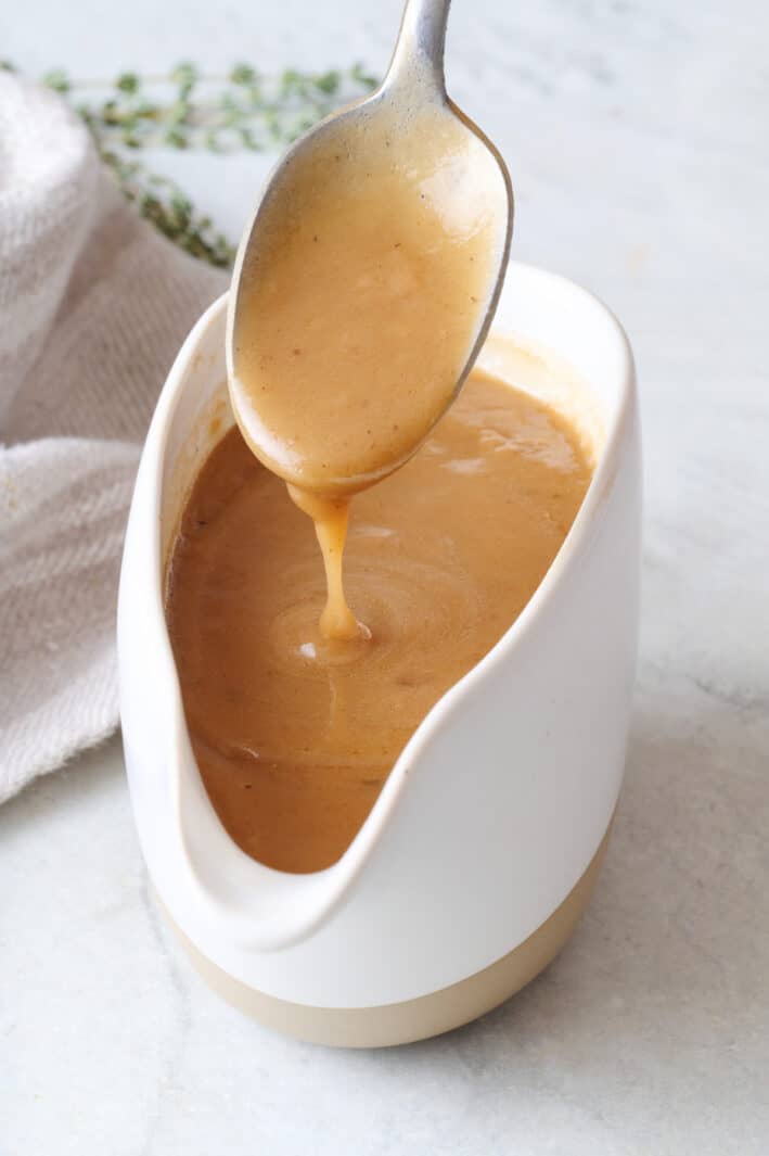 Spoon drizzling beef gravy back into gravy boat.