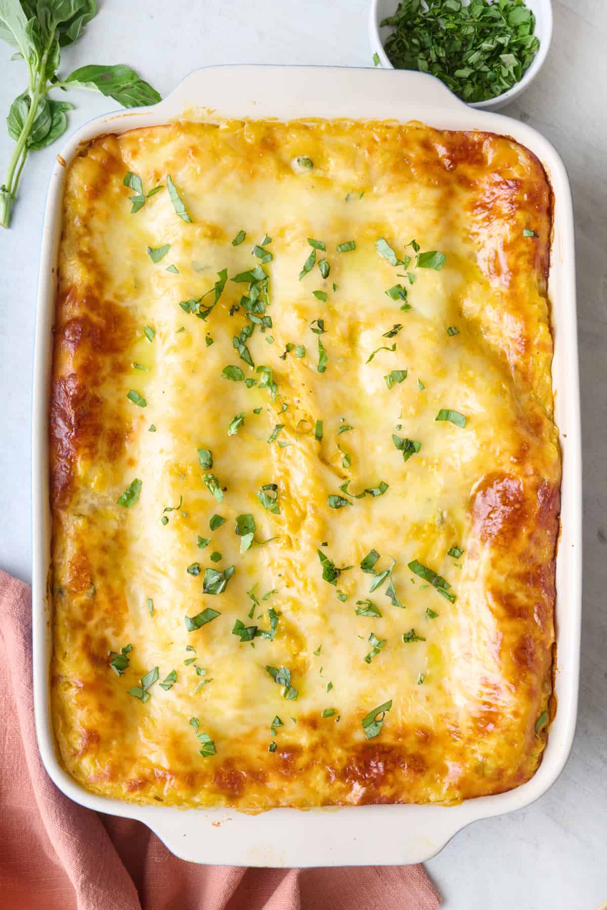 Butternut squash lasagna in a baking dish, garnished with fresh basil.