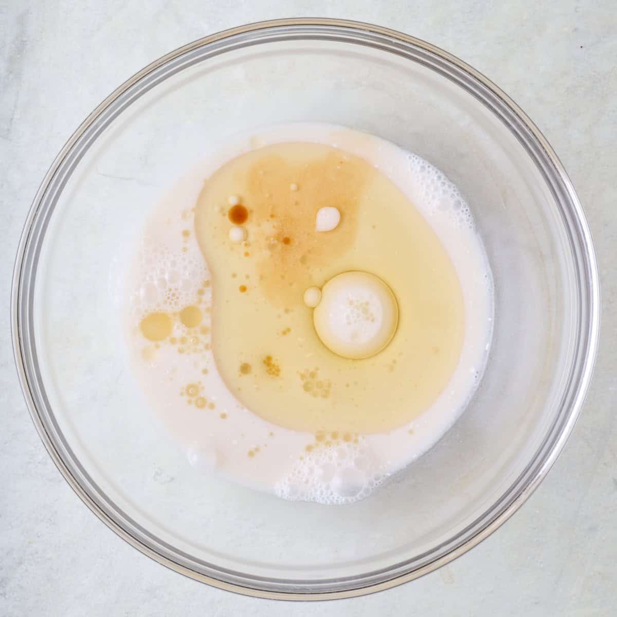 Milk, oil, maple syrup, and vanilla in a bowl before mixing.