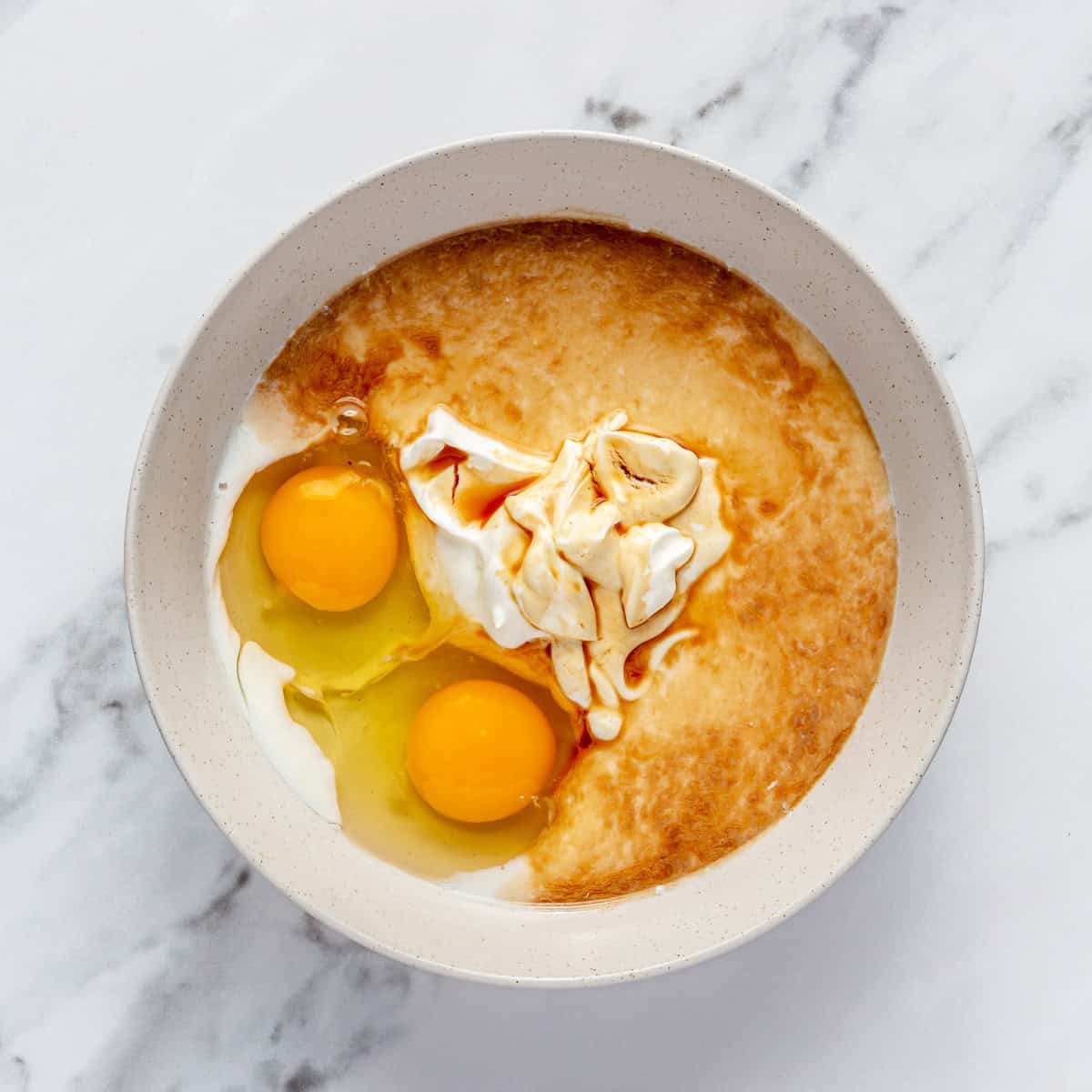 Eggs, yogurt, milk, and vanilla in a mixing bowl.