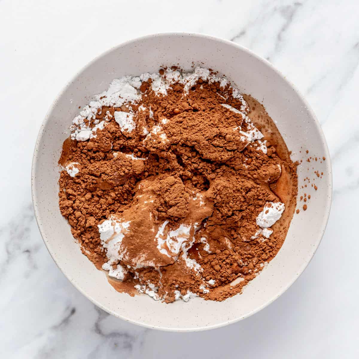 Powdered sugar, cocoa powder and milk in a small bowl.