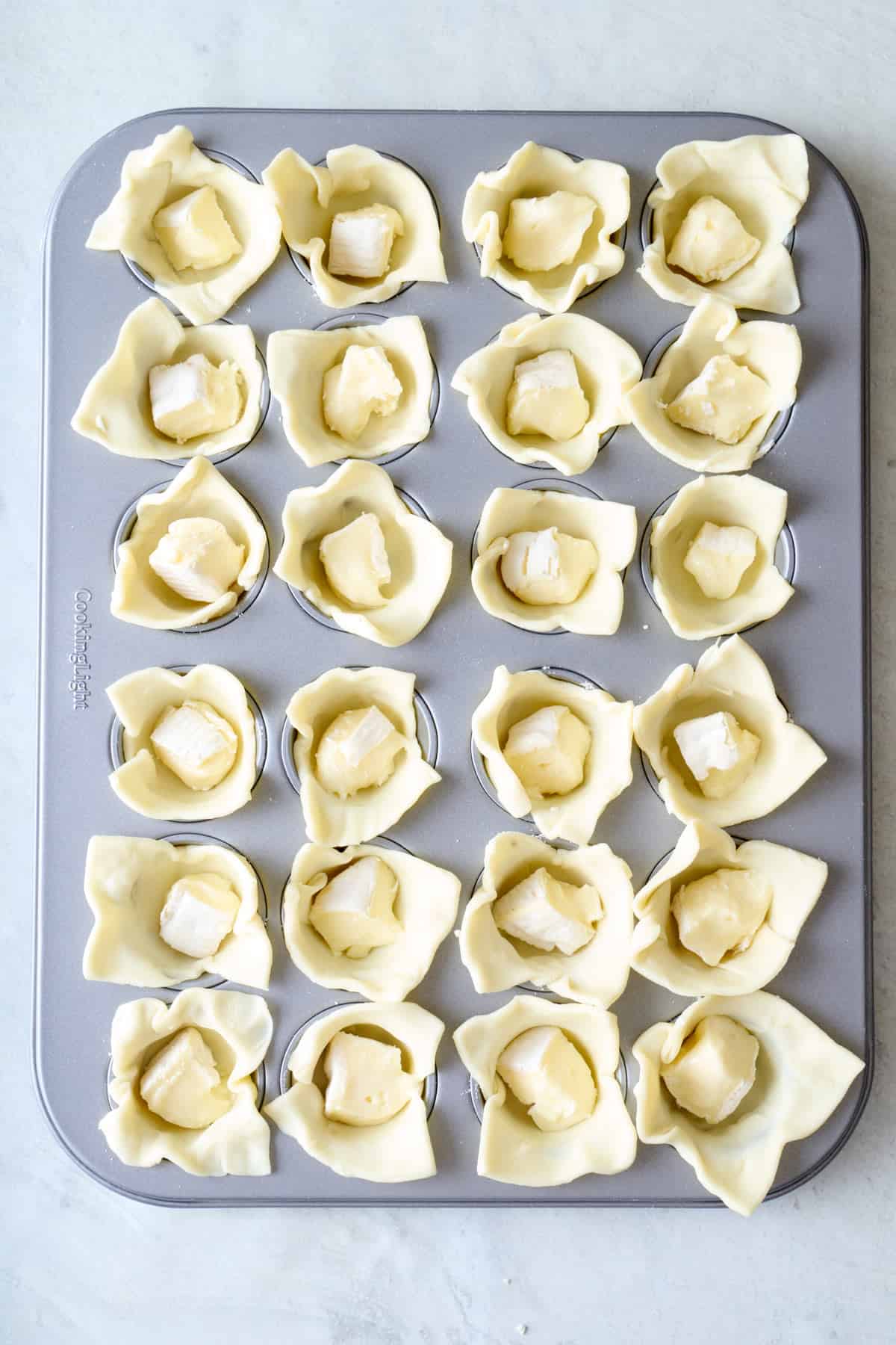 a piece of brie added to each pastry in the pan.