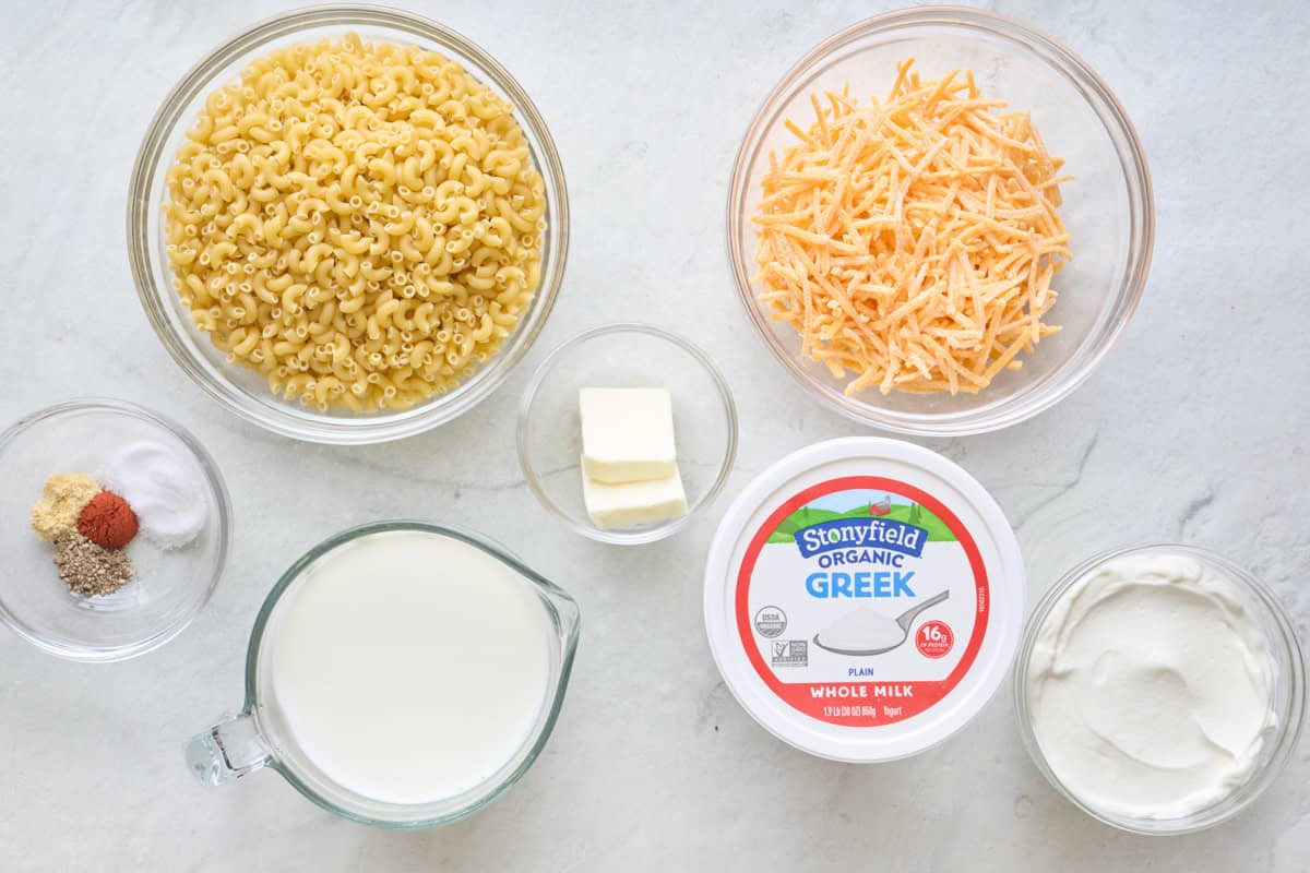 Ingredients for recipe: Stonyfield whole milk Greek yogurt container plus in a bowl, dry elbow pasta, spices, milk, butter, and shredded cheese.