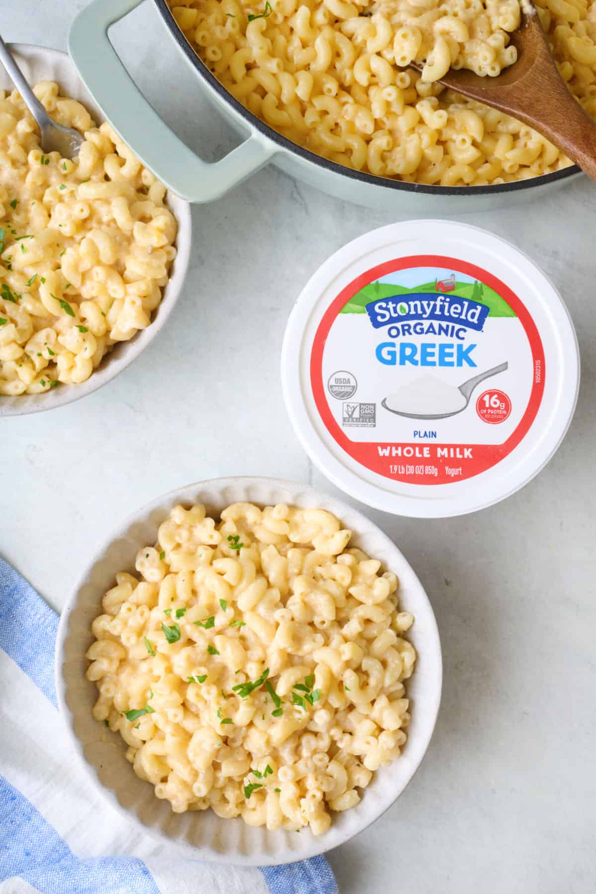 Serving of Greek yogurt mac and cheese in a bowl with container of Stonyfield Whole Milk Greek Yogurt container nearby.