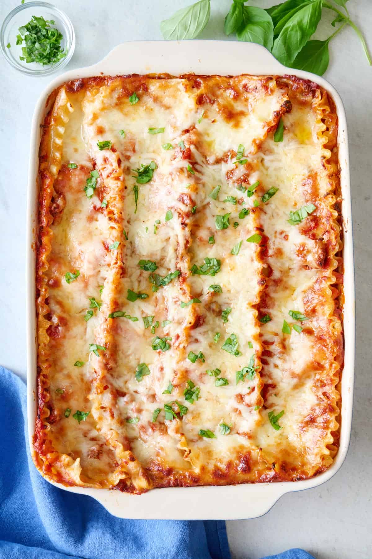 Homemade lasagna in a baking dish garnished with fresh basil.