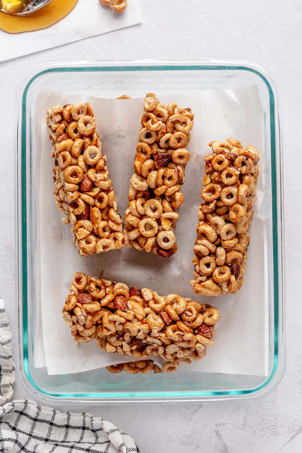 A few breakfast cereal bars in a storage container with pieces of parchment between each.