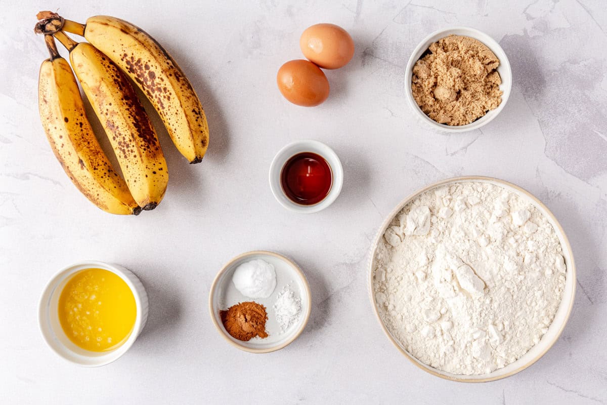 Ingredients for recipe: ripe bananas, melted butter, cinnamon, baking powder and baking soda, vanilla, eggs, brown sugar, and flour.