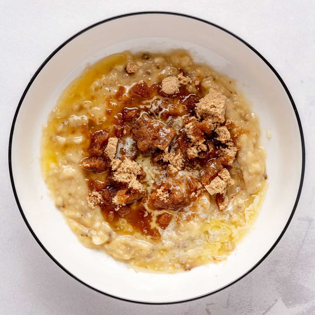 Mashed banana in bowl with brown sugar and melted butter added.