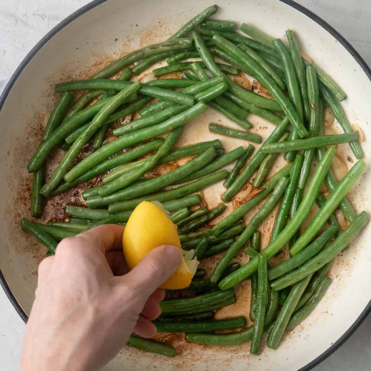 Lemon being squeezed into sauteed veggie.