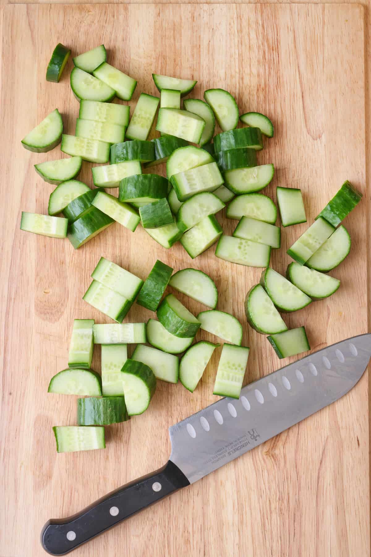 Cucumber cut into half moons on a cutting board.