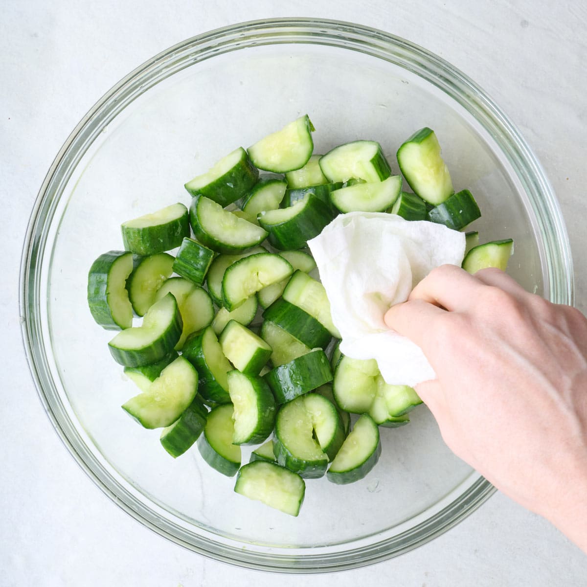 Drying cut cucumbers in a bowl with a paper towel.