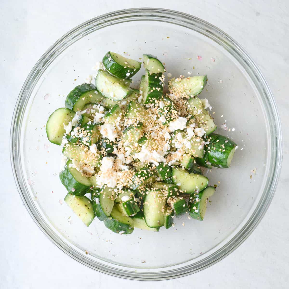 Feta and sesame seeds added on top of dressed cucumbers.