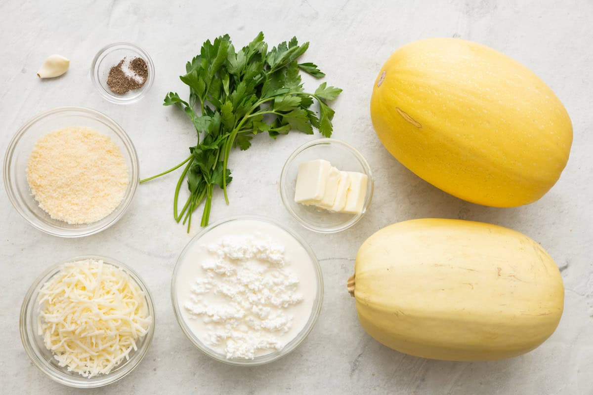 Ingredients for recipe: 2 spaghetti squash, butter, cottage cheese, parmesan cheese, garlic, salt and pepper, fresh parsley, and shredded mozzarella.