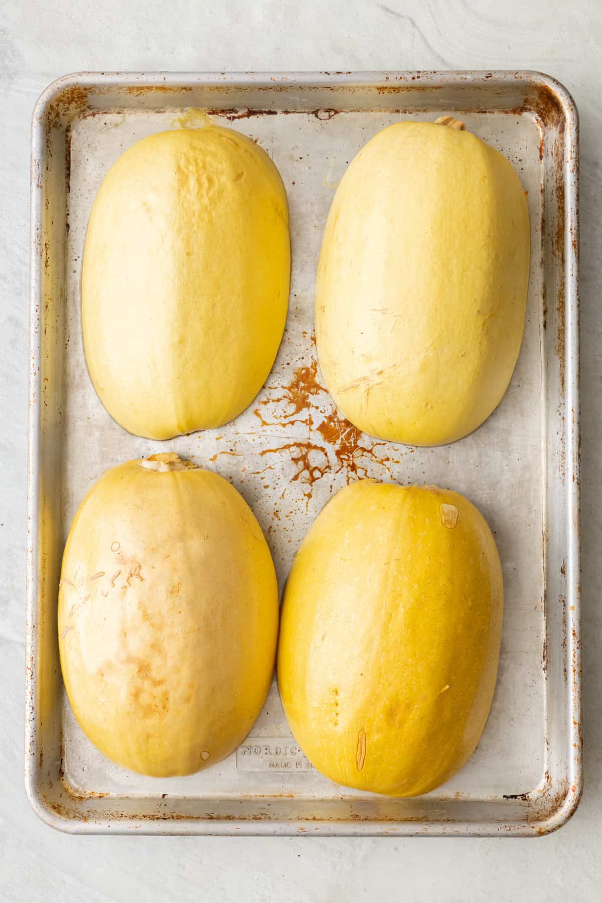 Squash halves flipped flesh side down on a baking sheet with water added to the pan before baking.