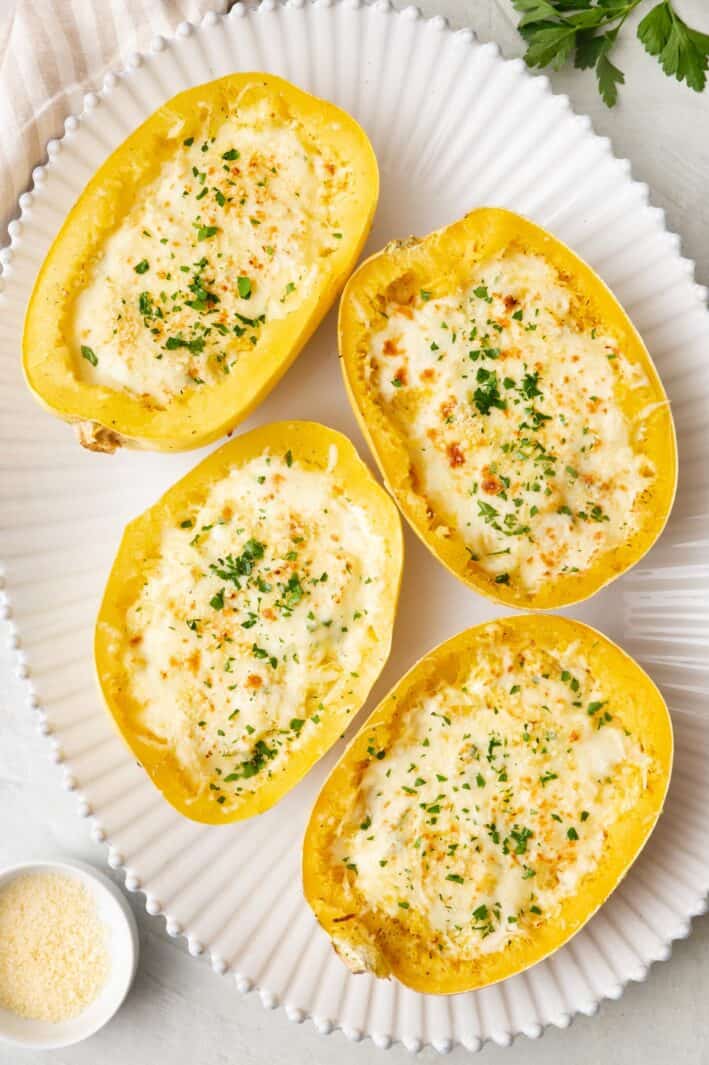 Four Spaghetti Squash Alfredo bowls on a large platter, garnished with fresh basil,