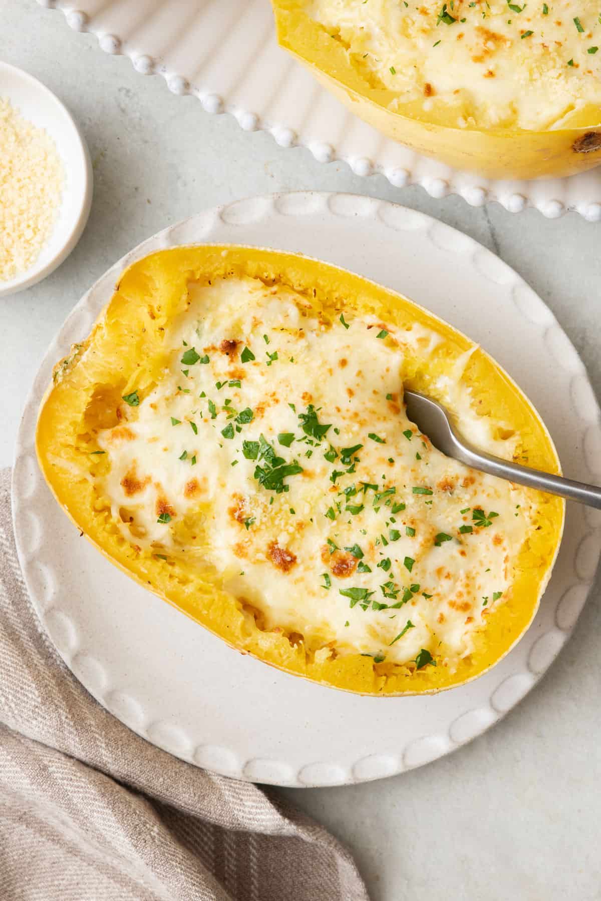 Spaghetti Squash Alfredo on a plate with a fork dipped inside squash.