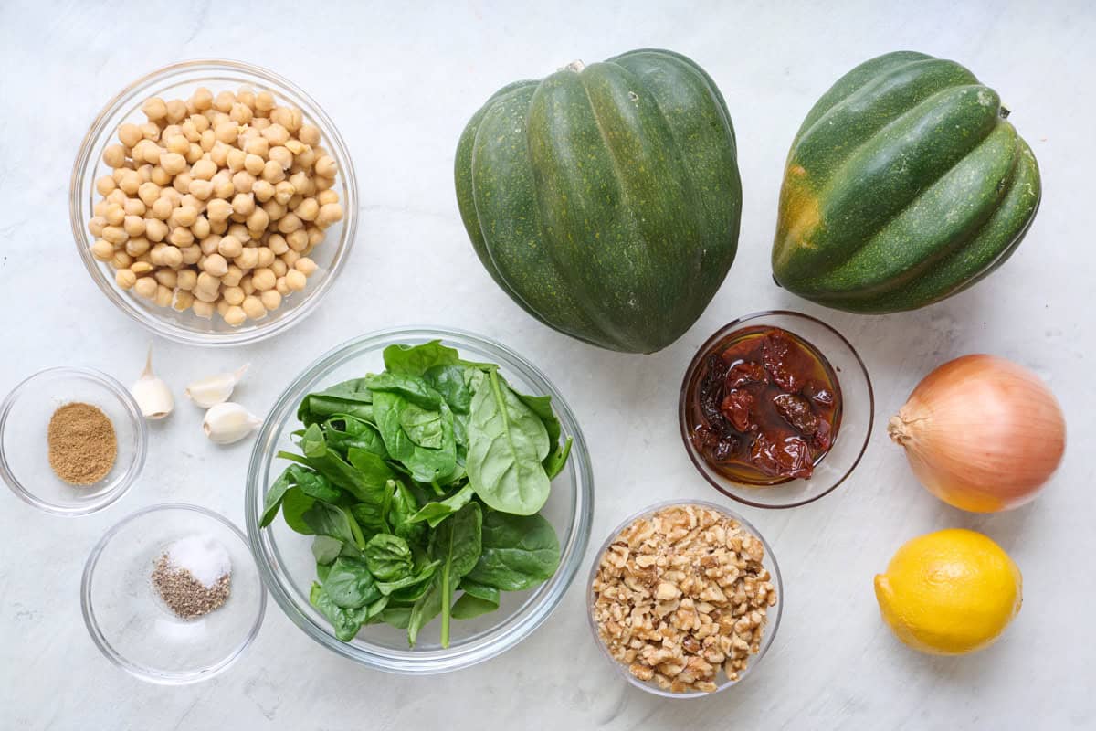 Ingredients for recipe: chickpeas, acorn squash, spinach, cumin, garlic, salt and pepper, sun dried tomatoes in oil, chopped walnuts, onion and lemon.