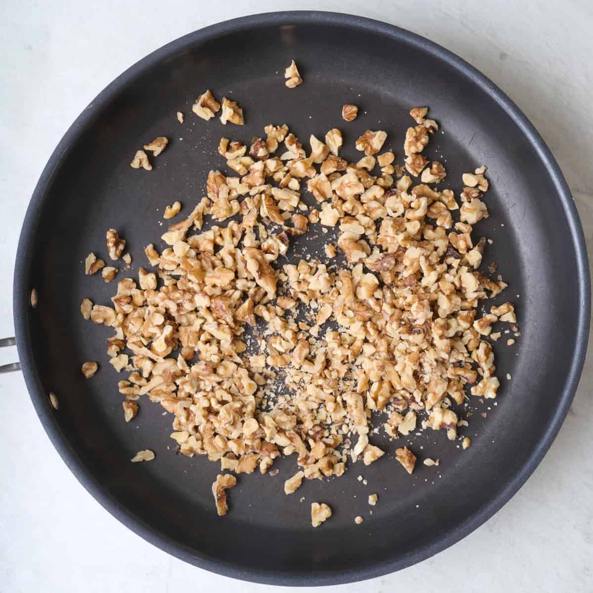 Chopped walnuts in a skillet.