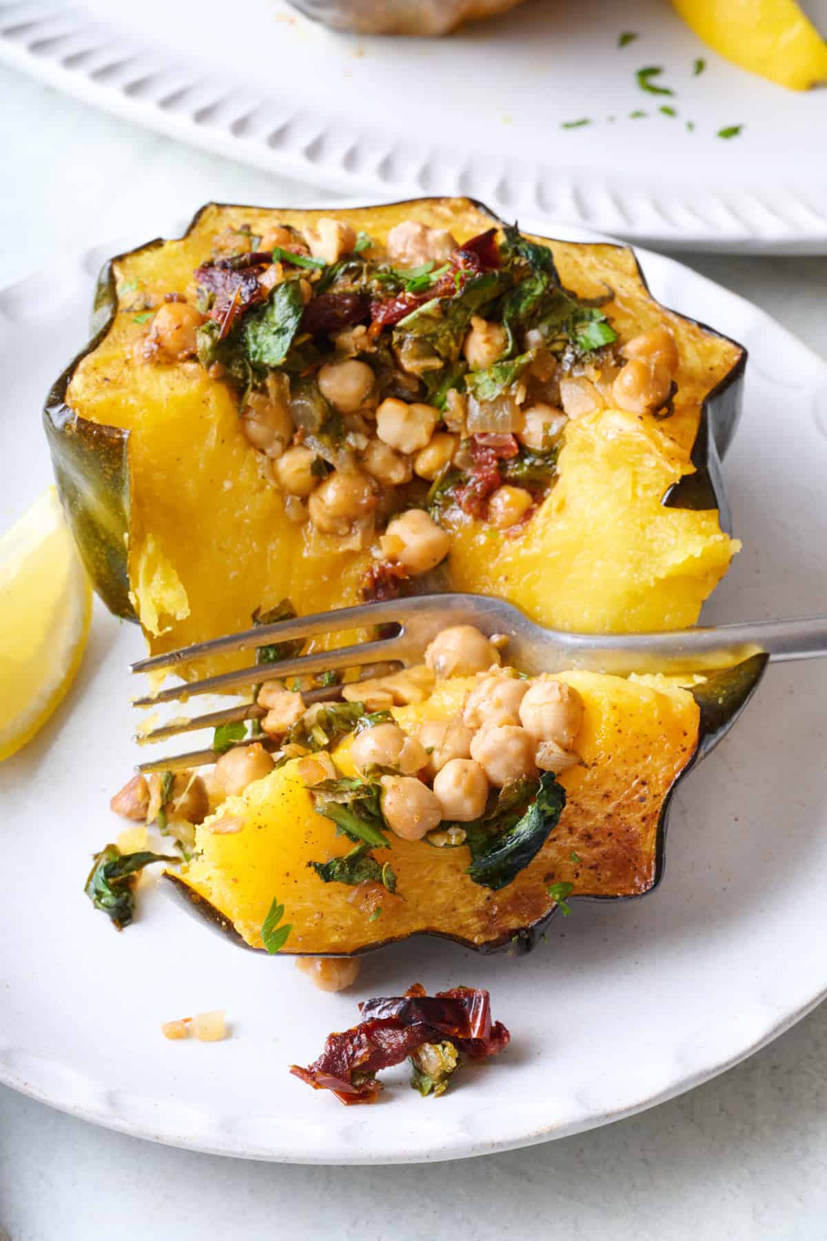 One stuffed acorn squash on a plate with a fork splitting in half to show inside.