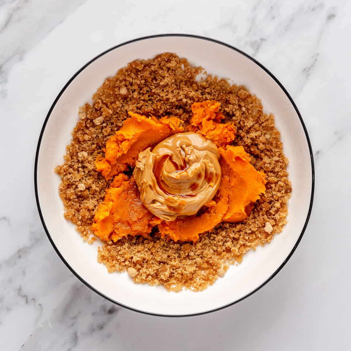 Butter and sugar mixture in a bowl with mashed sweet potatoes, nut butter, and vanilla added.