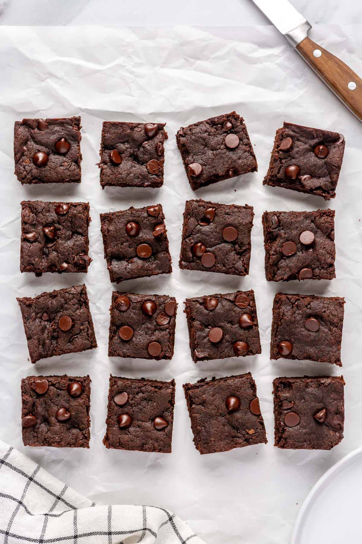 Sweet potato brownies on parchment paper cut into 16 squares.