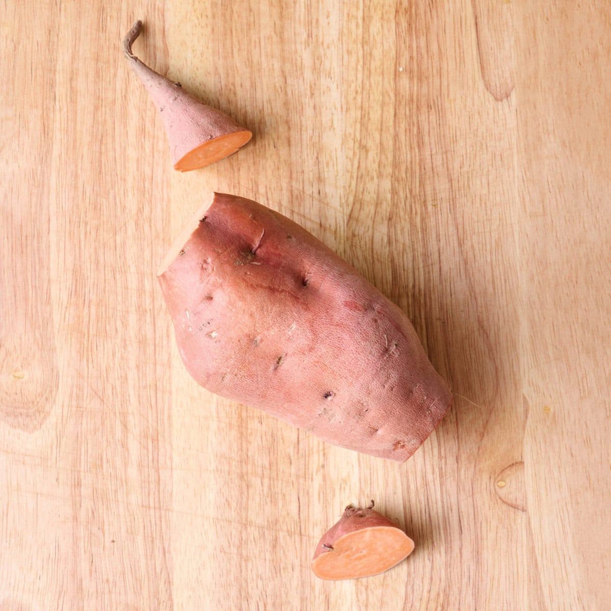 Sweet potato on cutting board with end pieces cut off.