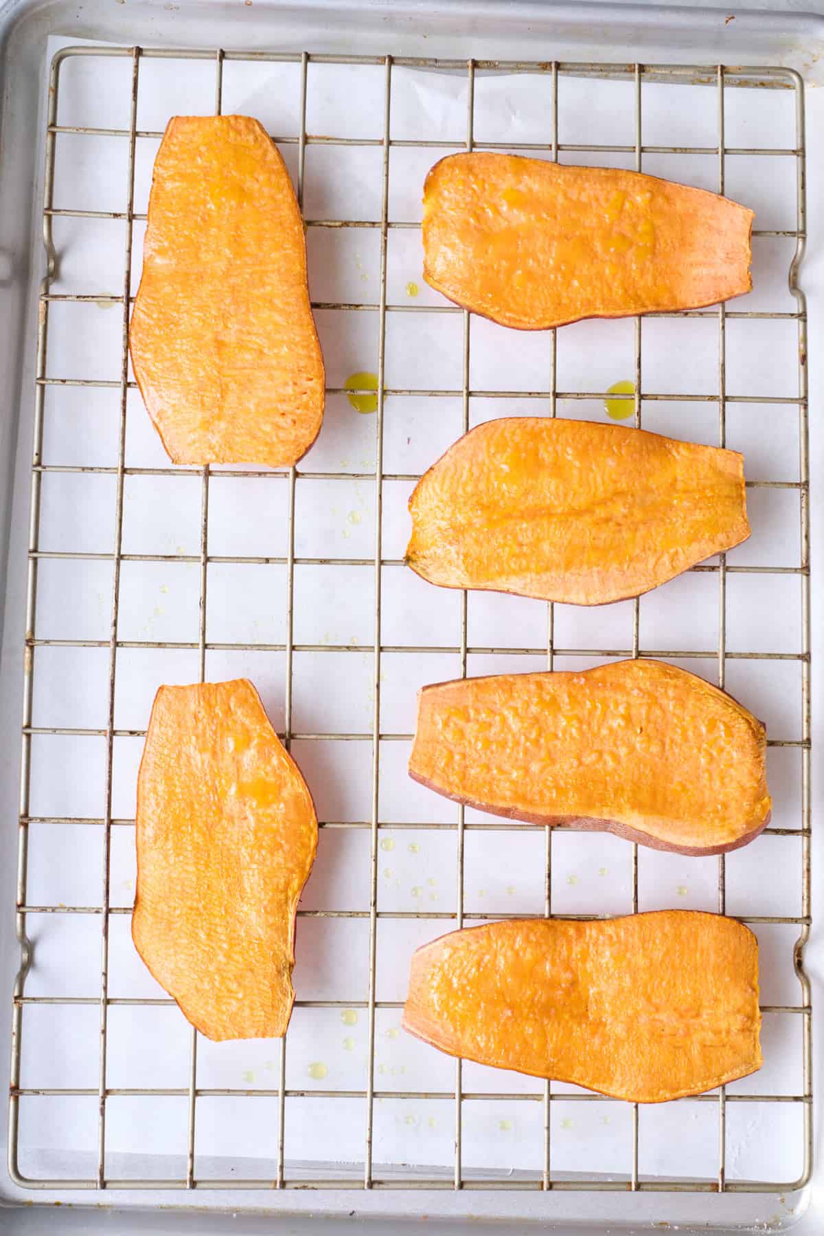 Roasted sweet potato planks on a wire rack on top of baking sheet.