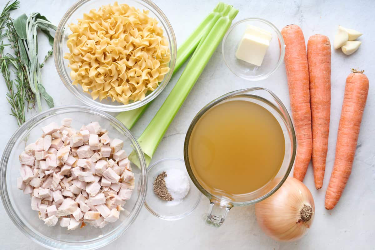 Ingredients for recipe: fresh herbs, uncooked egg noodles, diced turkey, celery, carrots, salt and pepper, butter, turkey broth, onion and garlic.