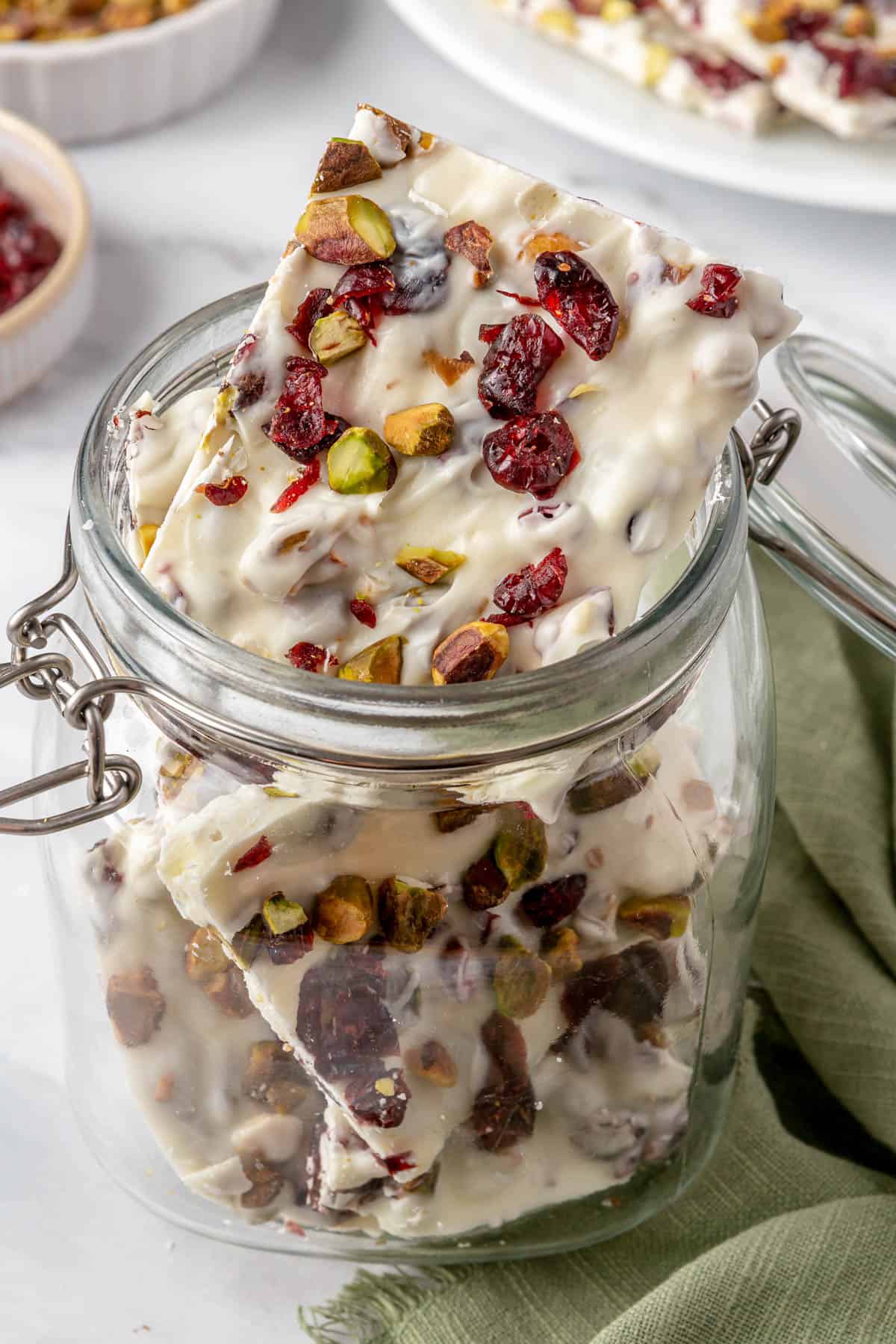 White chocolate bark squares in a small glass jar for storage.