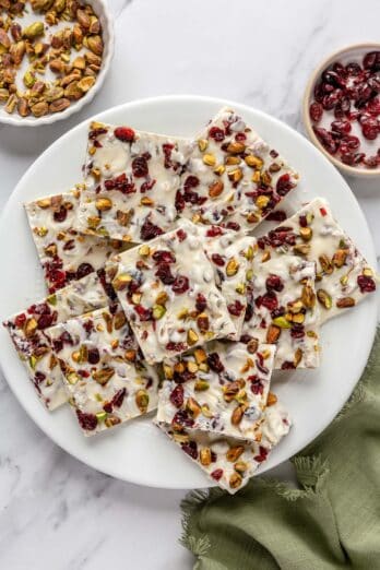 White chocolate bark squares with cranberries and pistachios on a round plate.