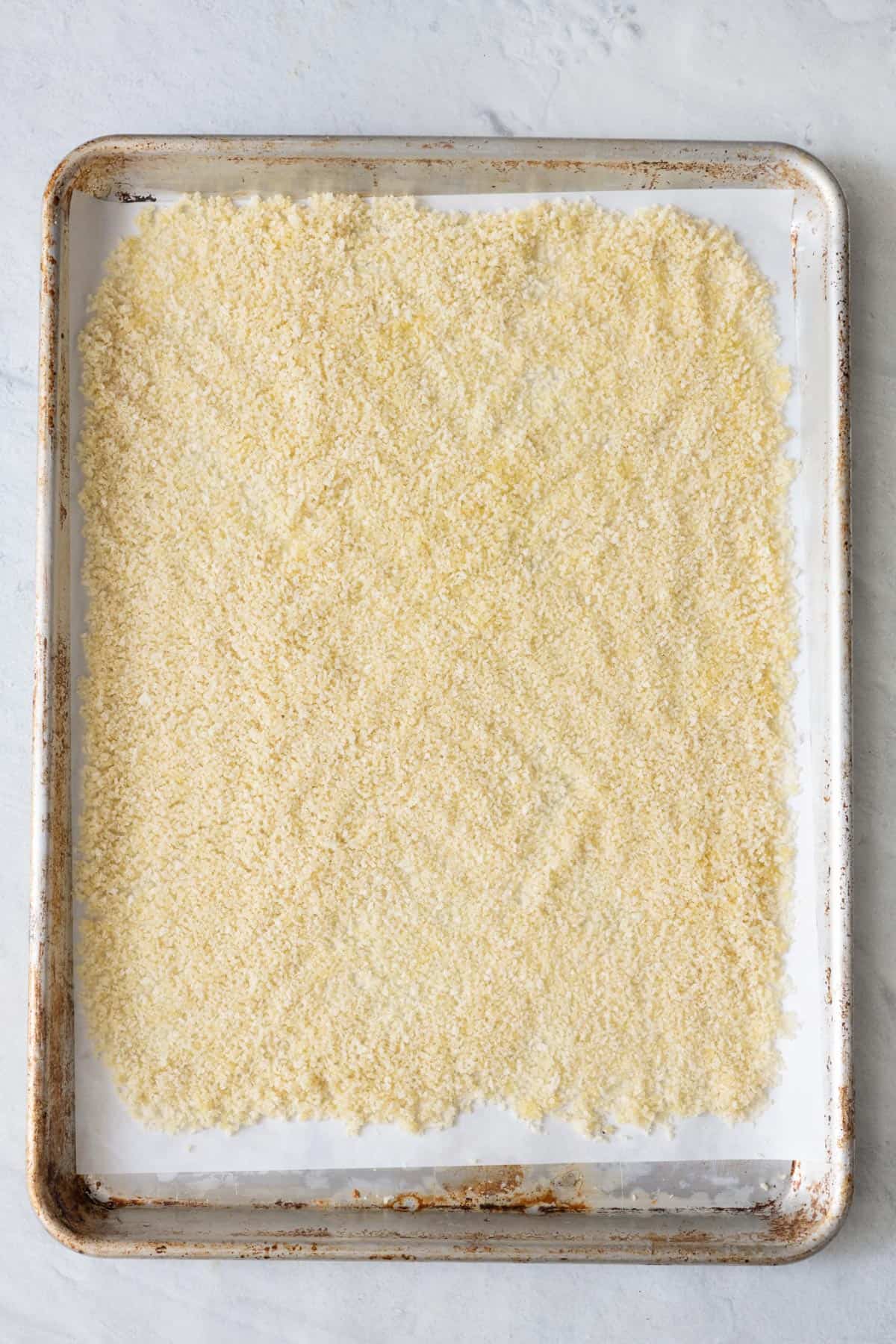 Breadcrumbs spread on a large sheet pan.