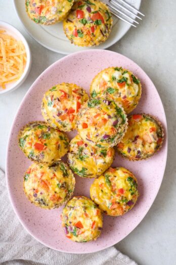 Veggie egg muffins on a small platter with a small plate of more nearby.