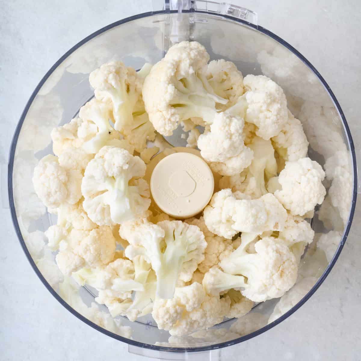 Cauliflower florets in food processor before processing.