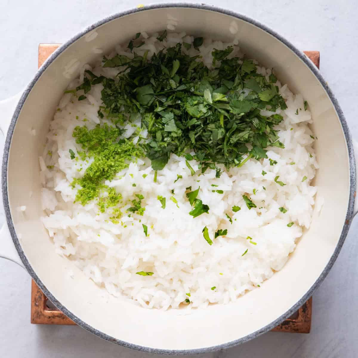 Cooked rice in a pot with cilantro and lime zest added.