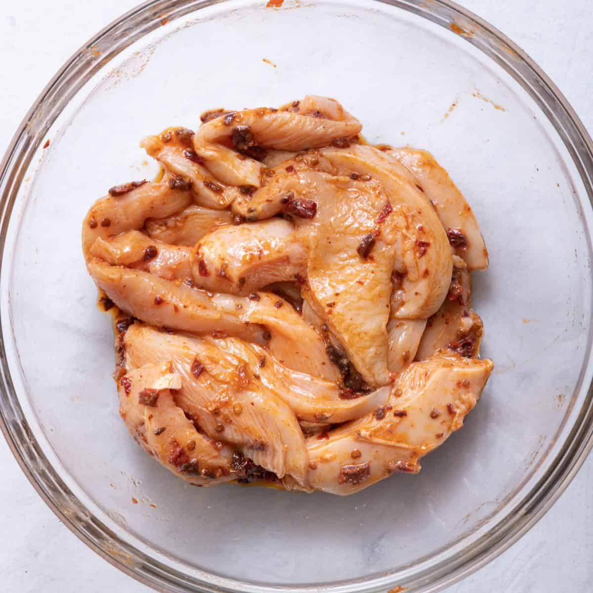 Chicken after tossing with seasonings in a bowl.