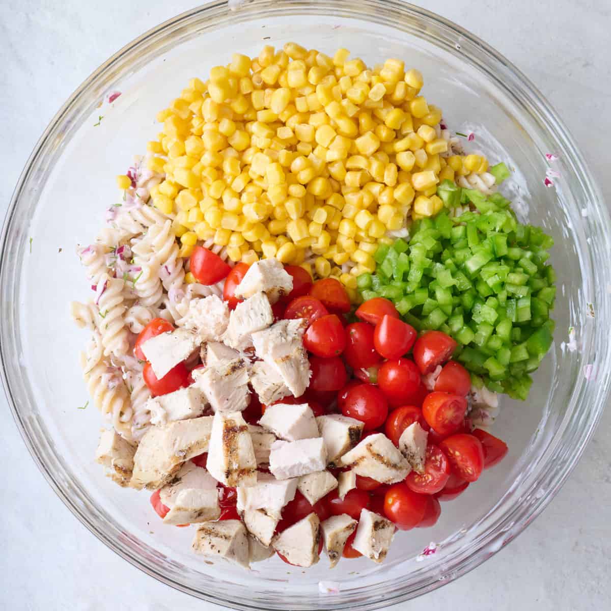 Corn, diced veggies, and chicken added to bowl with pasta and dressing.