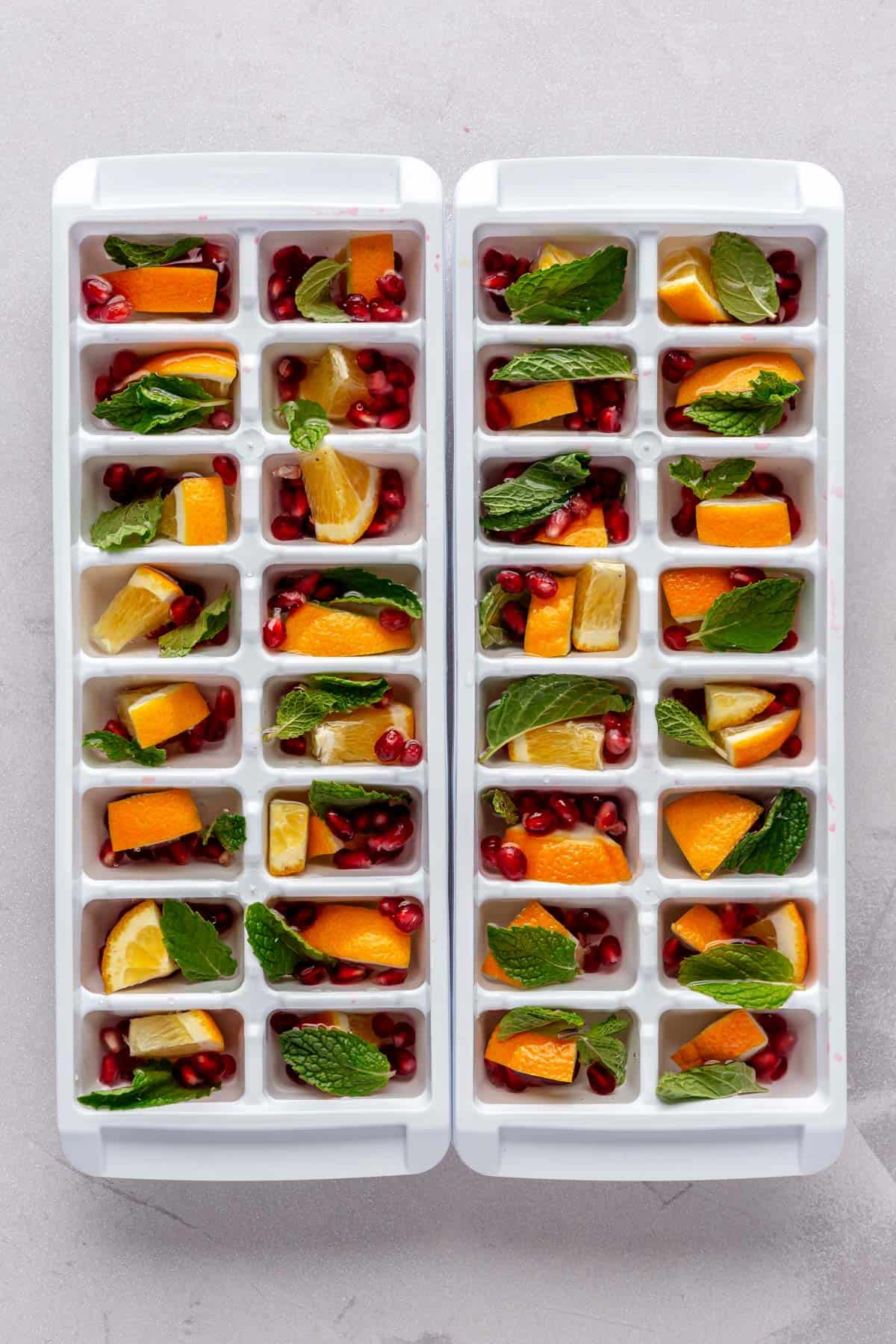 Ice cube trays filled with festive ice ingredients before freezing.