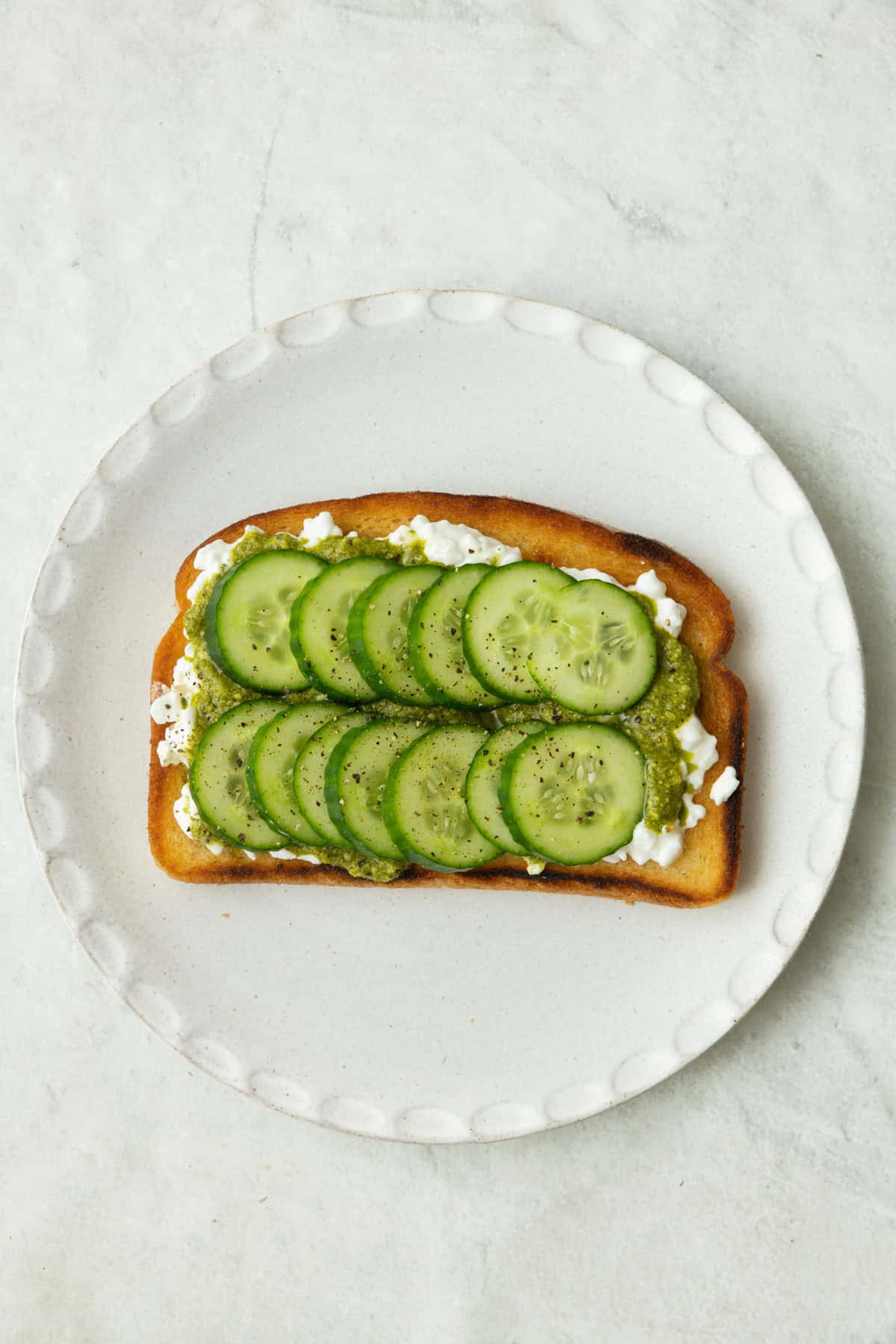 Toast with cottage cheese, pesto, and cucumbers.