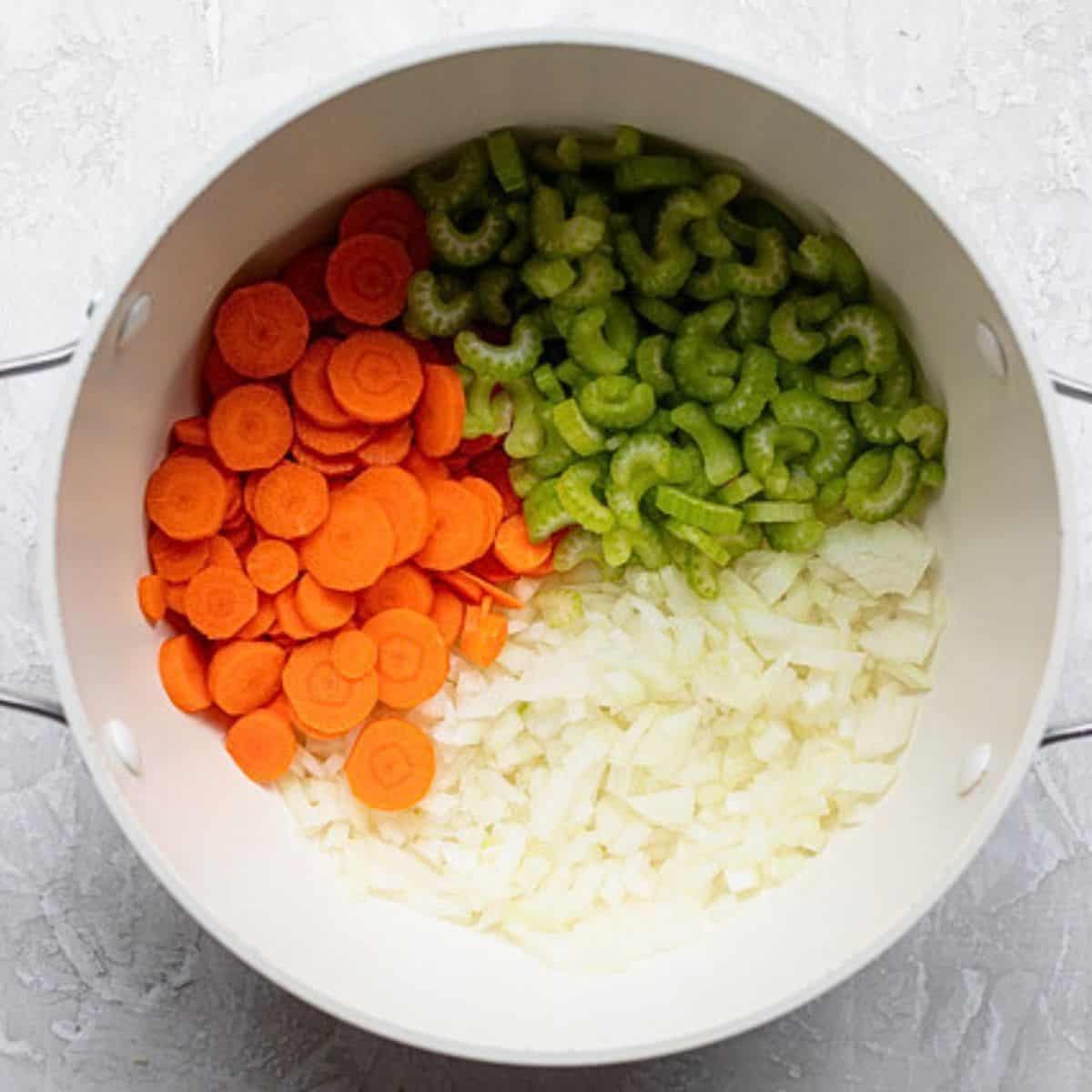 Carrots, celery, and onions in a pot.