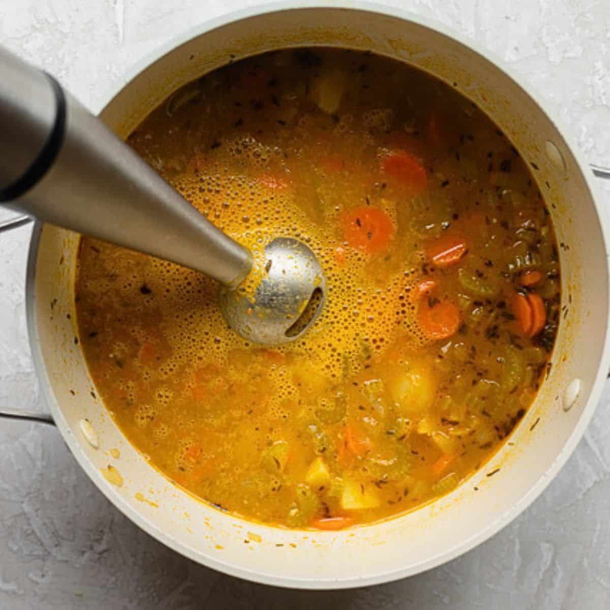 Immersion blender blending some of the soup.